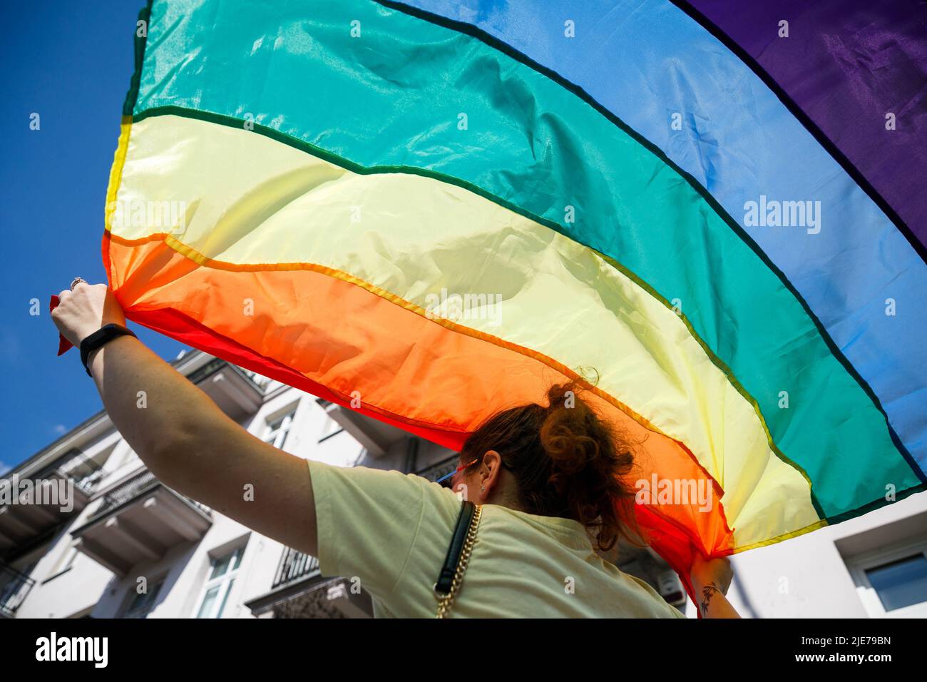 Warschau, Polen. 25.. Juni 2022. Eine Frau hält die Regenbogenfahne über ihrem Kopf, als sie an der Warschauer Gleichstellungsparade teilnimmt. Die Parade wurde organisiert, um die soziale Gleichheit zu fördern und die Aufmerksamkeit auf die Probleme der LGBT-Gemeinschaft in Polen zu lenken. In diesem Jahr fand auf der Warschauer Equality Parade die Kyiv Pride statt – die größte LGBTQ-Parade der Ukraine. Neben LGBTQ und Gleichstellungs-Slogans zeigten die Teilnehmer ihre Unterstützung gegen den Krieg und die Invasion Russlands in der Ukraine. (Foto von Volha Shukaila/SOPA Images/Sipa USA) Quelle: SIPA USA/Alamy Live News Stockfoto