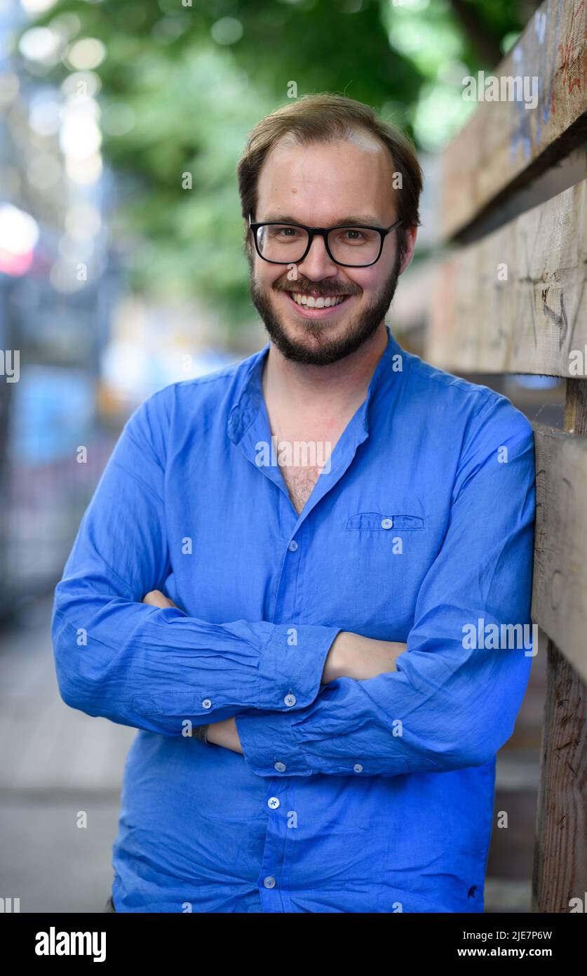 Berlin, Deutschland. 23.. Juni 2022. Maxim Edwards steht neben einem Bauzaun in Berlin-Mitte. Der 31-Jährige, der in Großbritannien aufgewachsen ist und jetzt als Journalist in Berlin lebt, beantragte die deutsche Staatsbürgerschaft auf der Grundlage eines Gesetzes, das vor einem Jahr geändert wurde, um die Einbürgerung von Opfern der Nazi-Verfolgung zu erleichtern und jetzt britischer und deutscher Staatsbürger ist. Nach dpa: Königsberg - Danzig - London - Berlin: Einbürgerung mit Hindernissen). Quelle: Bernd von Jutrczenka/dpa/Alamy Live News Stockfoto