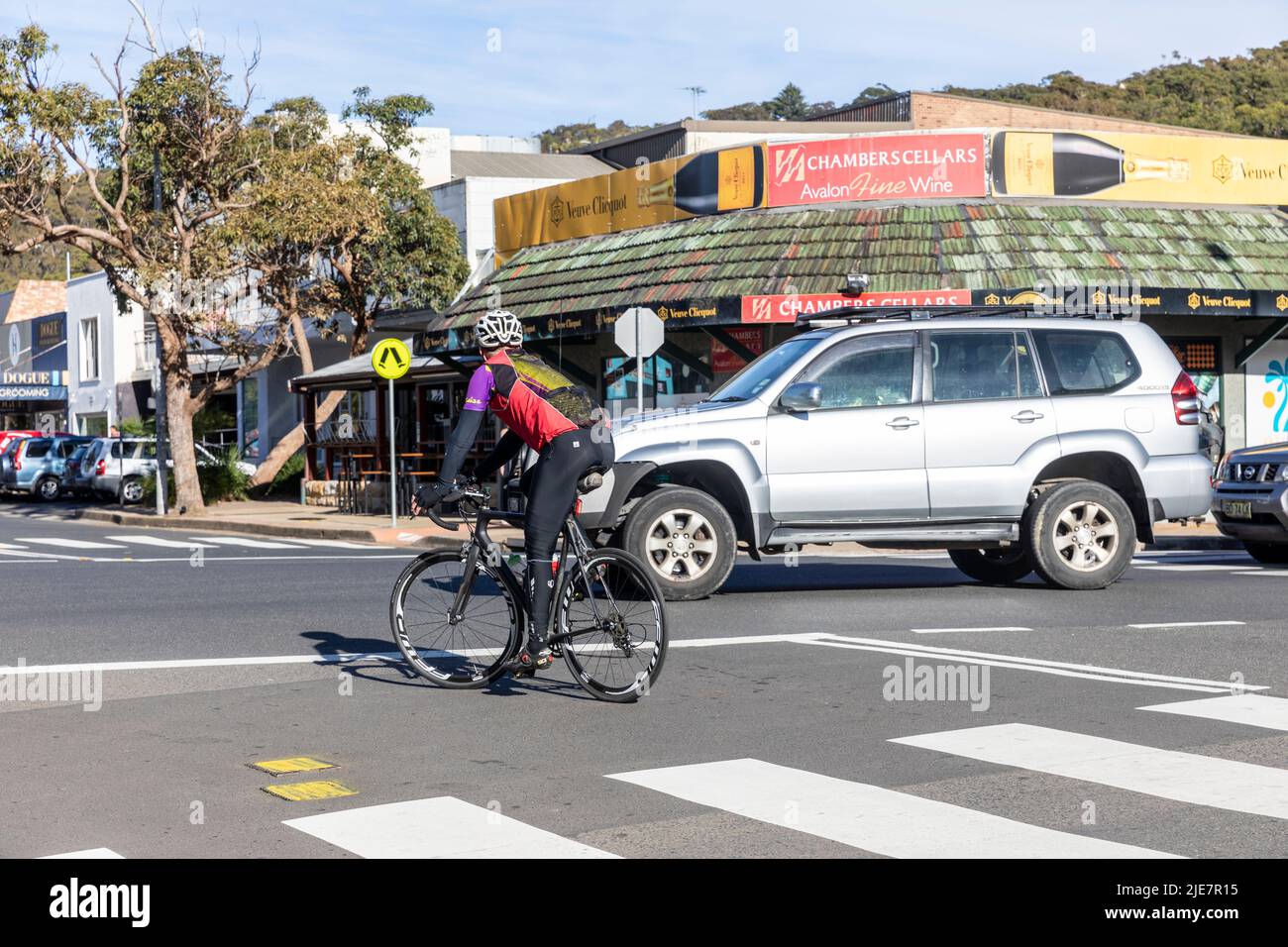 Australischer Radler auf dem Rennrad, vorbei an Zebrastreifen und Flaschengeschäft in Sydney, NSW, Australien, trainieren an einem Wintertag Radfahren mit Helm Stockfoto