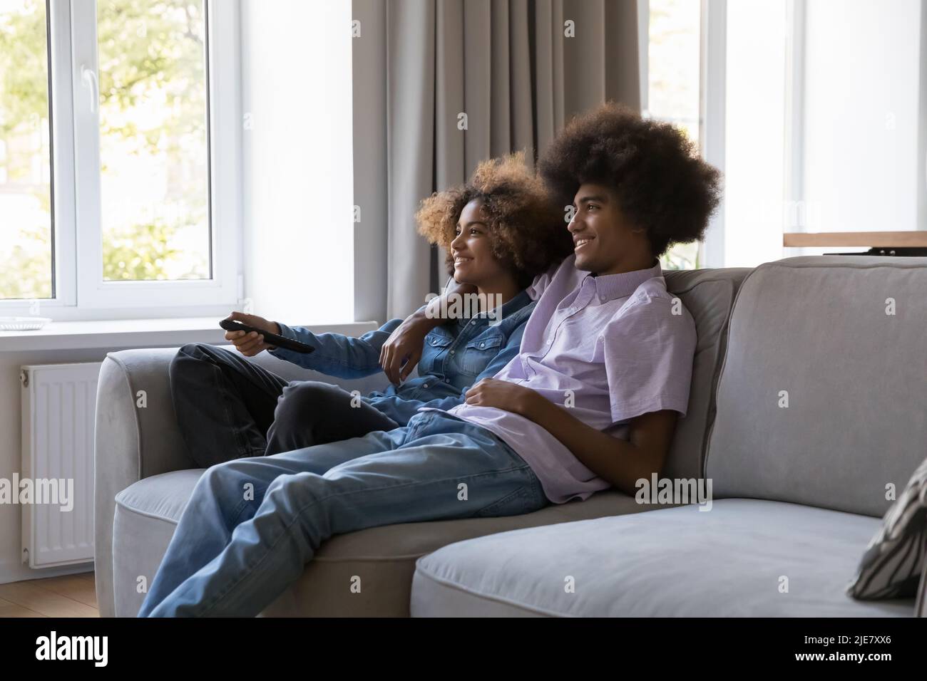 Afrikanisches Paar verbringt das Wochenende zu Hause, wechselt die Kanäle, schaut euch einen Film an Stockfoto