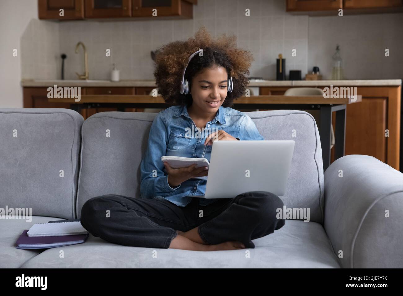 Mädchen tragen Kopfhörer macht Auftrag auf dem Sofa mit Laptop sitzen Stockfoto