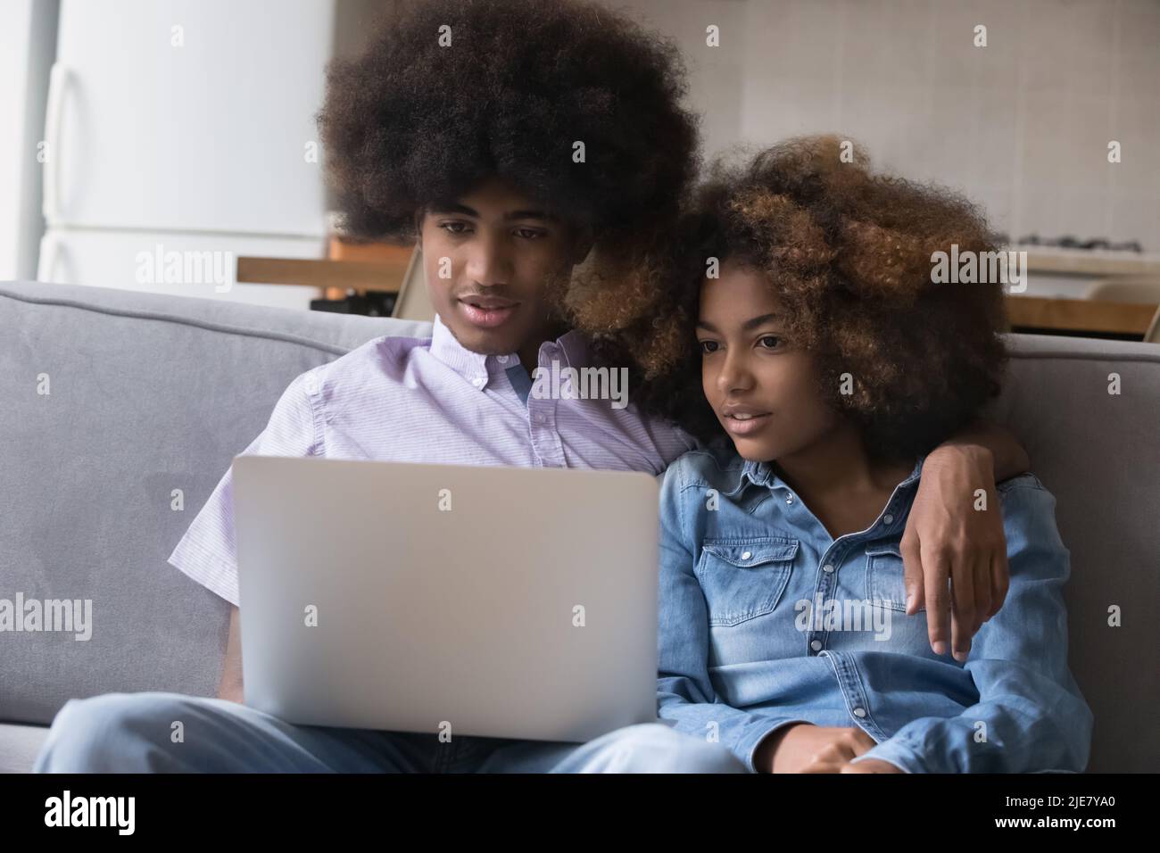 Das junge afrikanische Paar sitzt mit einem Laptop auf dem Sofa Stockfoto