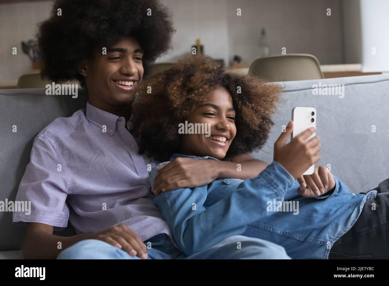 Teenager-Paar entspannen sich auf dem Sofa und haben Spaß mit dem Smartphone Stockfoto