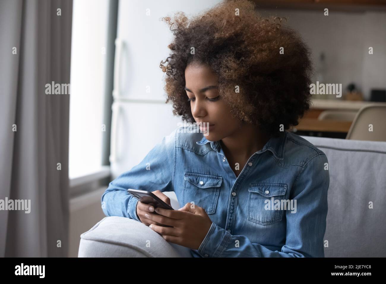 Afrikanisches Teenager-Mädchen liest Nachricht, sendet SMS mit dem Smartphone Stockfoto