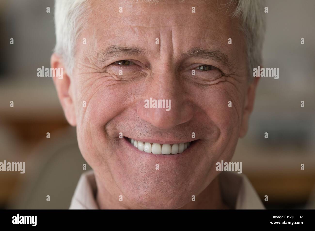 Ein älterer Mann mit einem breiten Lächeln starrte aus der Nähe auf die Kamera Stockfoto