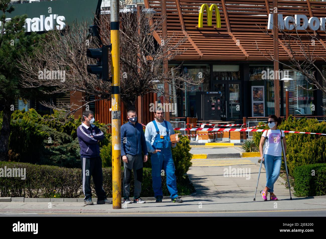 Frau mit schützender Gesichtsmaske, die während der Pandemie von Covid 19 2020 vor dem geschlossenen McDonald's Fast-Food-Restaurant für normale Geschäfte steht Stockfoto