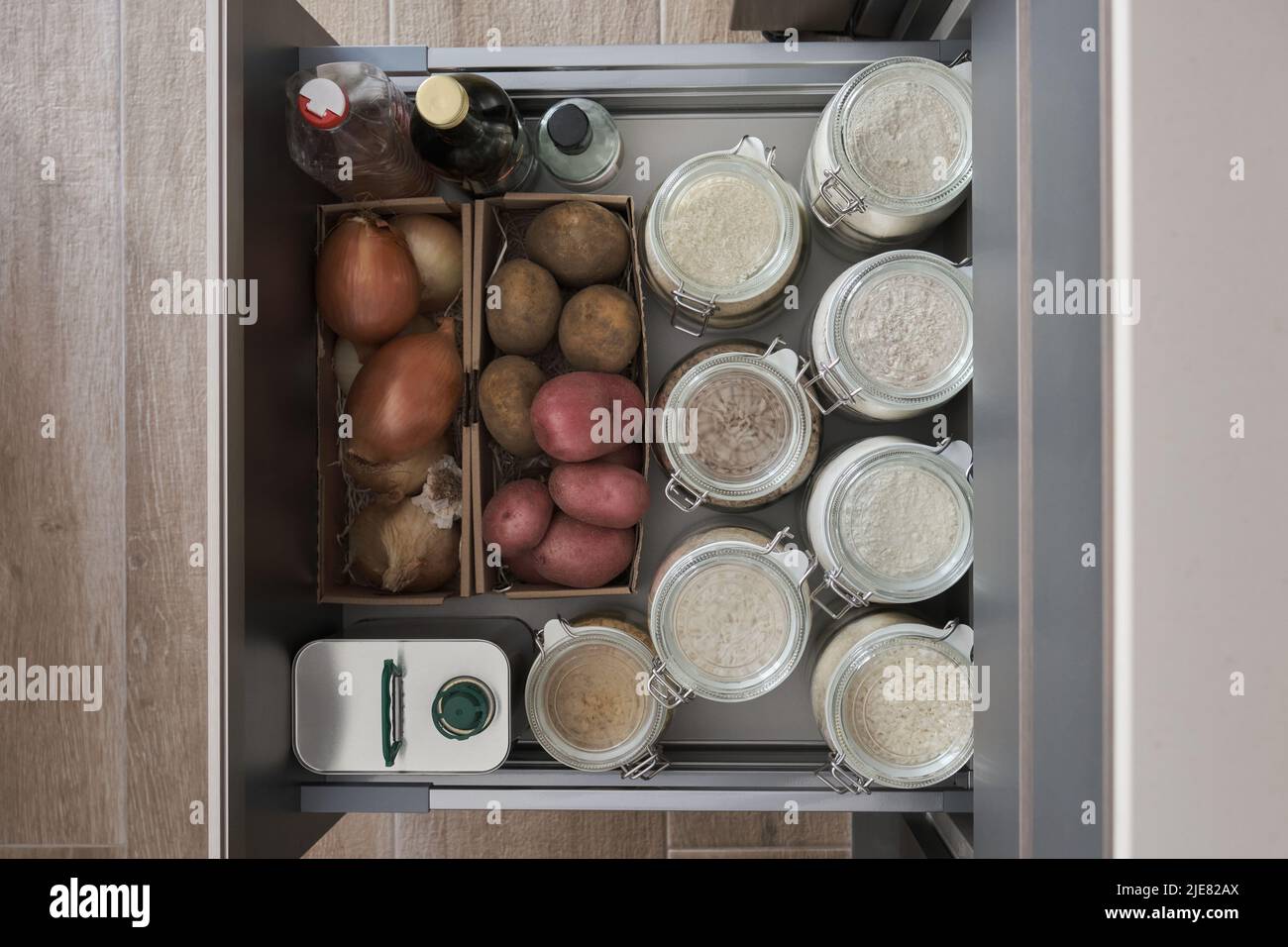 Verschiedene Mehle, Ries, Kartoffeln, Zwiebeln, Öl, Essig in der Küchenschublade. Stockfoto