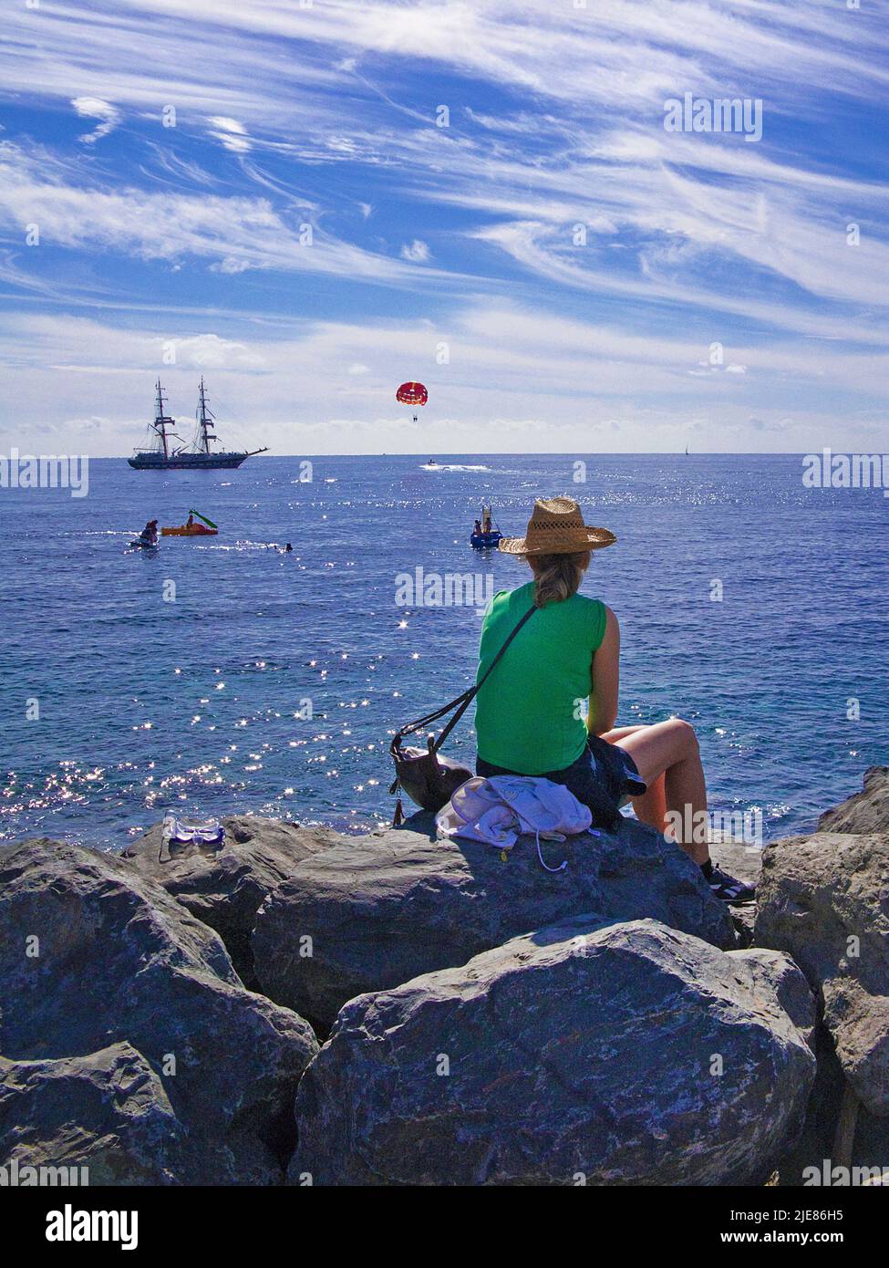 Frau, die auf einem Felsen am Strand sitzt und den Atlantik, Puerto de Mogan, den Kanarischen Inseln, den Kanarischen Inseln, Spanien, Europa Stockfoto