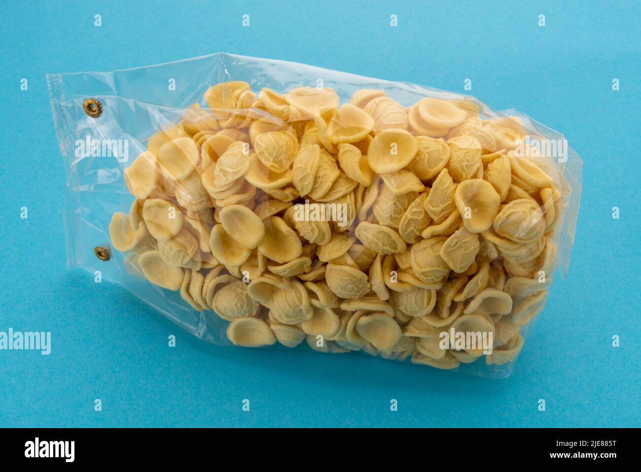 Orecchiette Pasta in transparent versiegelte Verpackung zum Verkauf auf blauem Hintergrund, italienische Pasta aus Apulien mit Hartweizenmehl und Wasser, typisch Stockfoto
