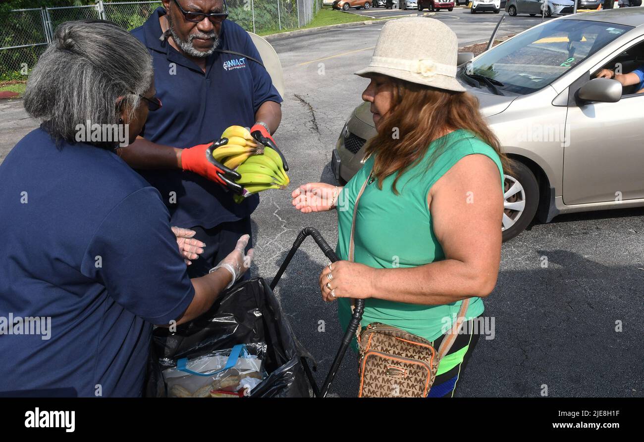 Orlando, Usa. 25.. Juni 2022. Freiwillige geben Bananen an eine Frau bei einer Nahrungsmittelverteilungsveranstaltung für Bedürftige, die von der Second Harvest Food Bank of Central Florida und Orange County in der St. John Vianney Church in Orlando, Florida, gesponsert wird. Hohe Lebensmittel- und Gaspreise drücken die arbeitenden Familien unter Druck und schicken einige zum ersten Mal in Lebensmittelvorratskammern, aber die Anbieter kämpfen mit den Inflationskosten, da die Nachfrage steigt. Kredit: SOPA Images Limited/Alamy Live Nachrichten Stockfoto