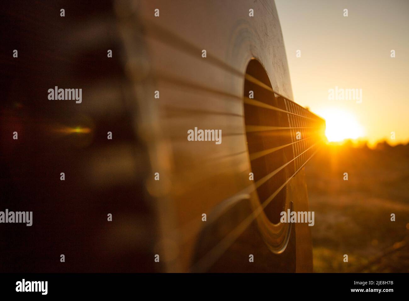 Gitarre während des Sonnenuntergangs. Gitarre spielen mit ein paar Freunden während der goldenen Stunde in der Natur, nur eine Stunde vor Einbruch der Nacht. Gitarre und Sonnenuntergang. Stockfoto