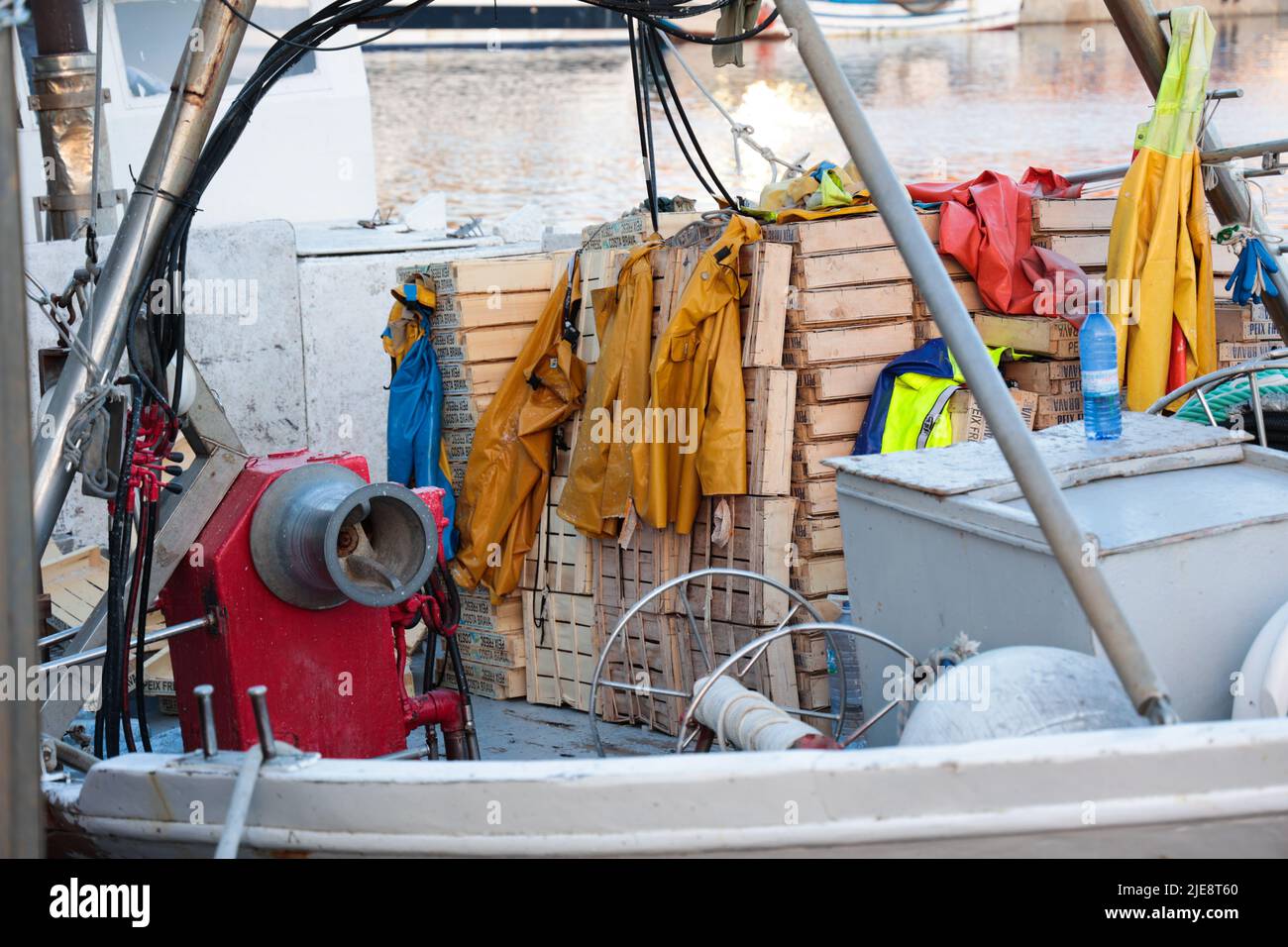 Die gelbe wasserdichte Schutzkleidung von Fisherman wird auf einem kommerziellen Fischerboot in Katalonien, Spanien, zum Trocknen zurückgelassen Stockfoto