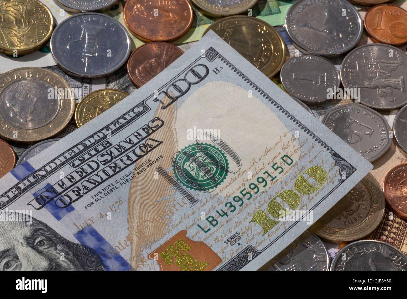 Nahaufnahme eines 100-Dollar-Banknotens, der auf Münzen verschiedener Währungen liegt Stockfoto