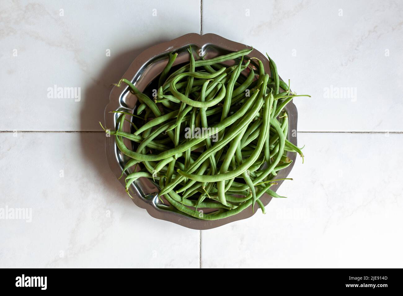 Rohe grüne Bohnen auf einem Metalltablett auf Marmorboden, Draufsicht Stockfoto