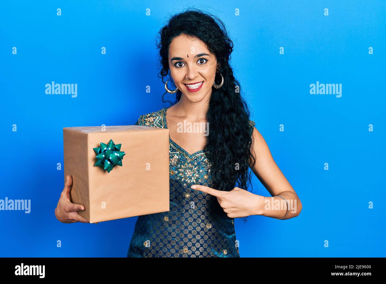 Junge Frau trägt Bindi und traditionelle Kurta Kleid halten Geschenk lächelnd glücklich zeigen mit Hand und Finger Stockfoto