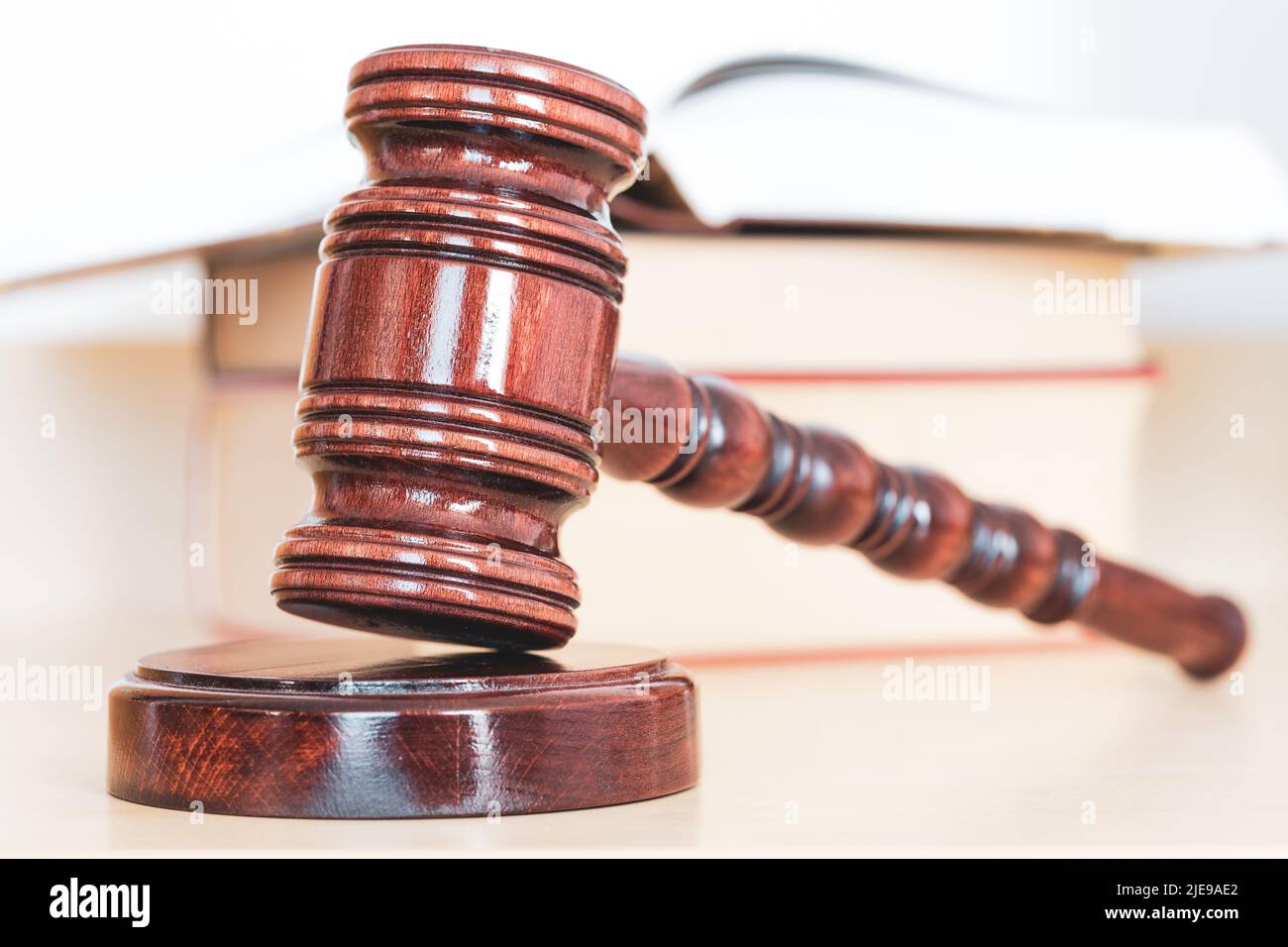Öffnen Sie ein Gesetzbuch mit einem hölzernen Richter-Gavel auf dem Tisch in einem Gerichtssaal oder Strafverfolgungsbüro Stockfoto