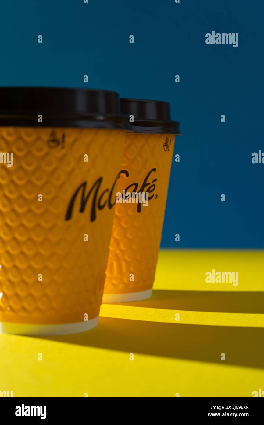 Ukraine, Kiew - 17. Februar 2021: Gelbes Glas Kaffee von McDonald's. Papierglas Getränk McCafe. Kaffeetasse auf Tisch mit Schatten. Speisekarte im Fastfood-Restaurant. Stockfoto