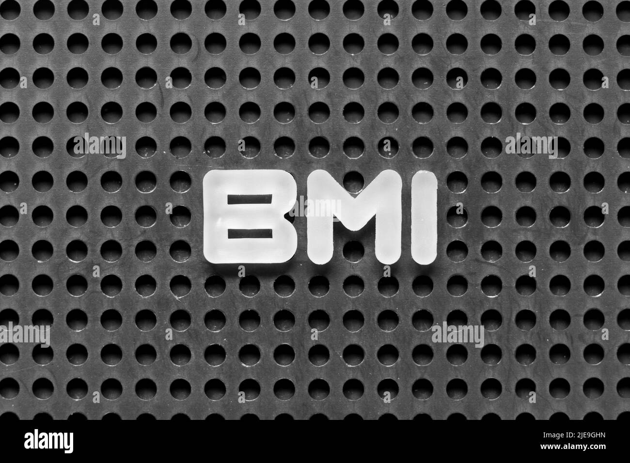 Weißer Buchstabe im Wort BMI (Abkürzung für Body-Mass-Index) auf schwarzem Hintergrund der Leiterplatte Stockfoto