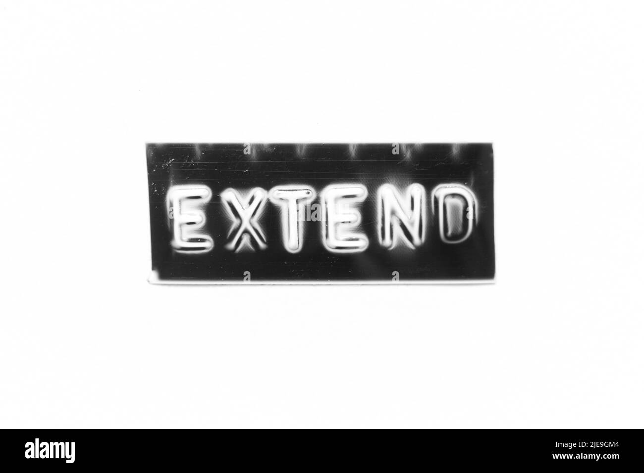 Schwarzes Banner mit geprägtem Buchstaben und Wort extend auf weißem Papierhintergrund Stockfoto