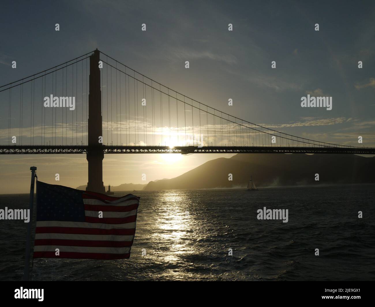 Sonnenuntergang über der Golden Gate Bridge mit US-Flagge im Vordergrund Stockfoto