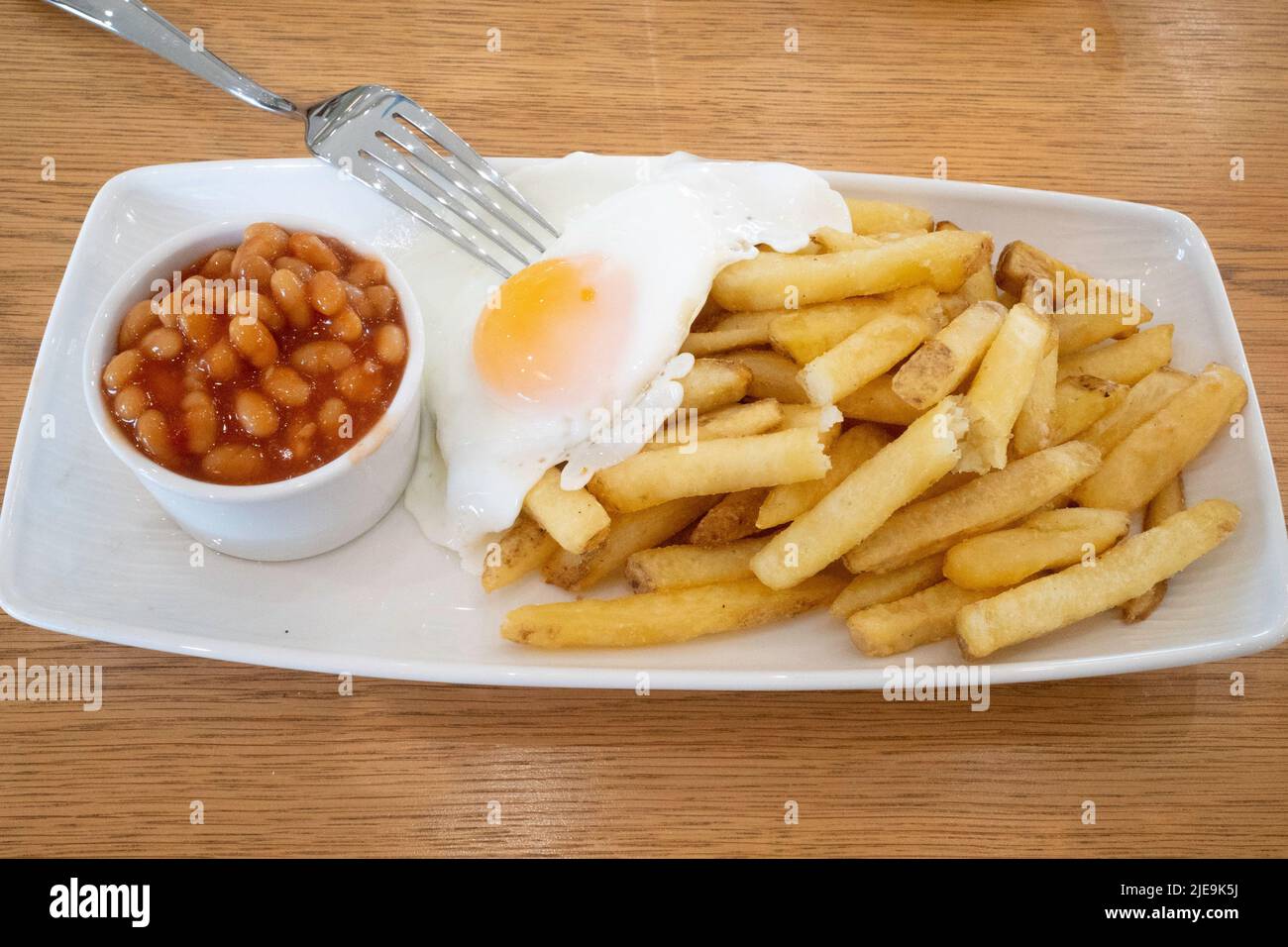 Ein leichtes Frühstück mit gebratenen, mit Eiern gebackenen Bohnen und Chips im von Kirkleatham ummauerten Gartencafé Stockfoto
