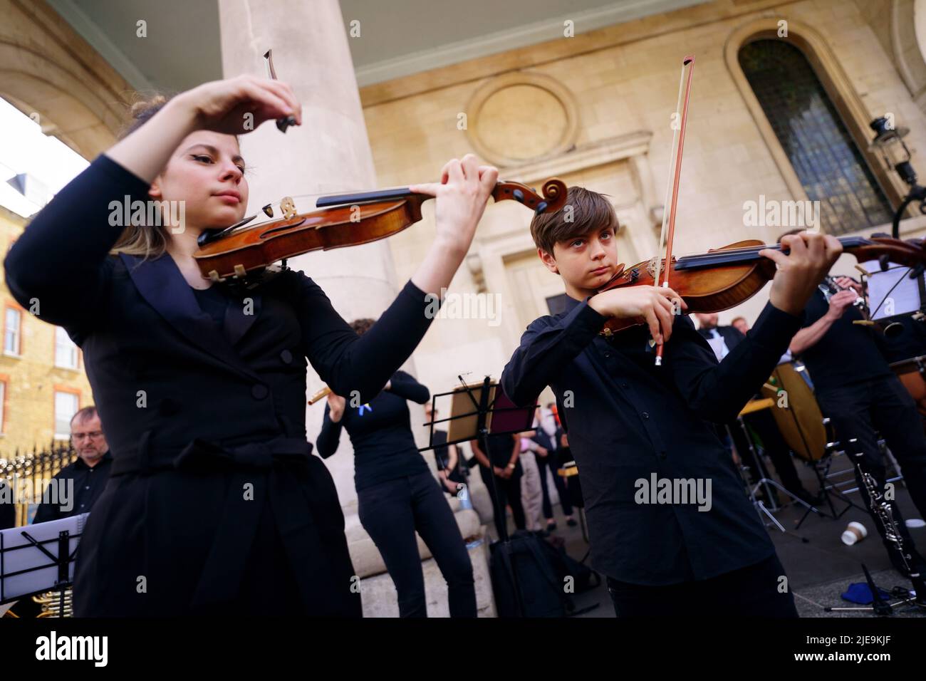 Der 11-jährige ukrainische Geiger Corey Sheldunov (rechts) nimmt an einer Aufführung von Peter und dem Wolf des ukrainischen Komponisten Sergey Prokofjew Teil, mit dem Playing for Peace Orchestra - das Sir Michael Palin als Sprecher, den anglo-russischen Dirigenten Petr Limonov, Und der Enkel des Komponisten Gabriel Prokofjew am französischen Horn - vor der St. Paul's Church, Covent Garden, im Zentrum Londons. Die Musiker des Playing for Peace Orchestra kommen aus den besten Orchestern Londons und die Aufführung ist dabei, Geld für den humanitären Appell des Katastrophenschutzkomitees (DEC) in der Ukraine zu sammeln. Bild da Stockfoto