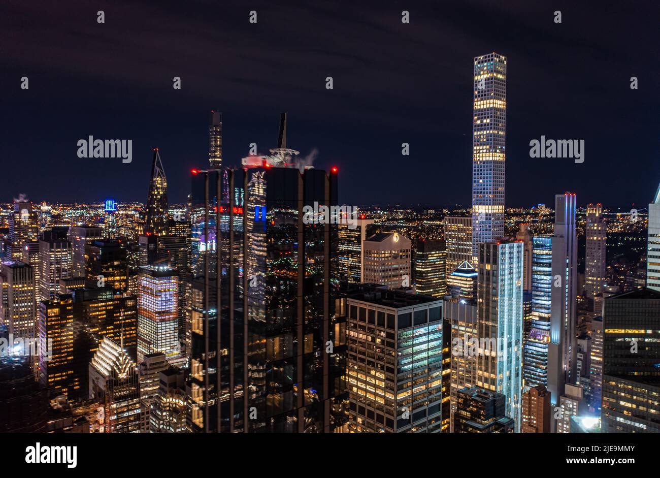 Nächtliche Stadtszene mit modernen Hochhäusern in der Metropole. Dunkle, glänzende Glasfassade, die die umliegenden Lichter reflektiert. Manhattan, New York City, USA Stockfoto