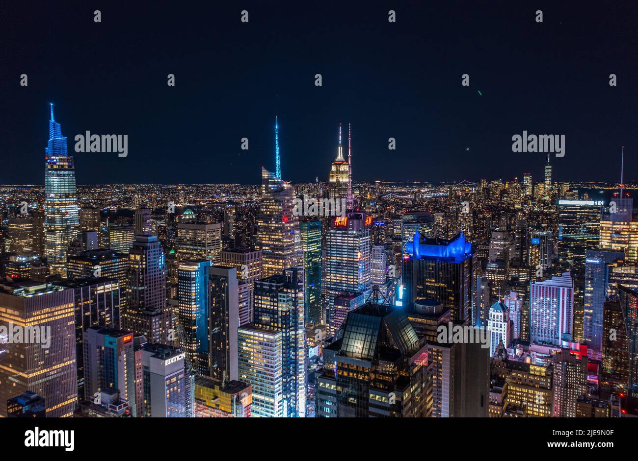 Tausende von Lichtern in der großen Stadt in der Nacht. Luftpanoramabbild von hoch aufragenden, farbig beleuchteten Gebäuden. Manhattan, New York City, USA Stockfoto