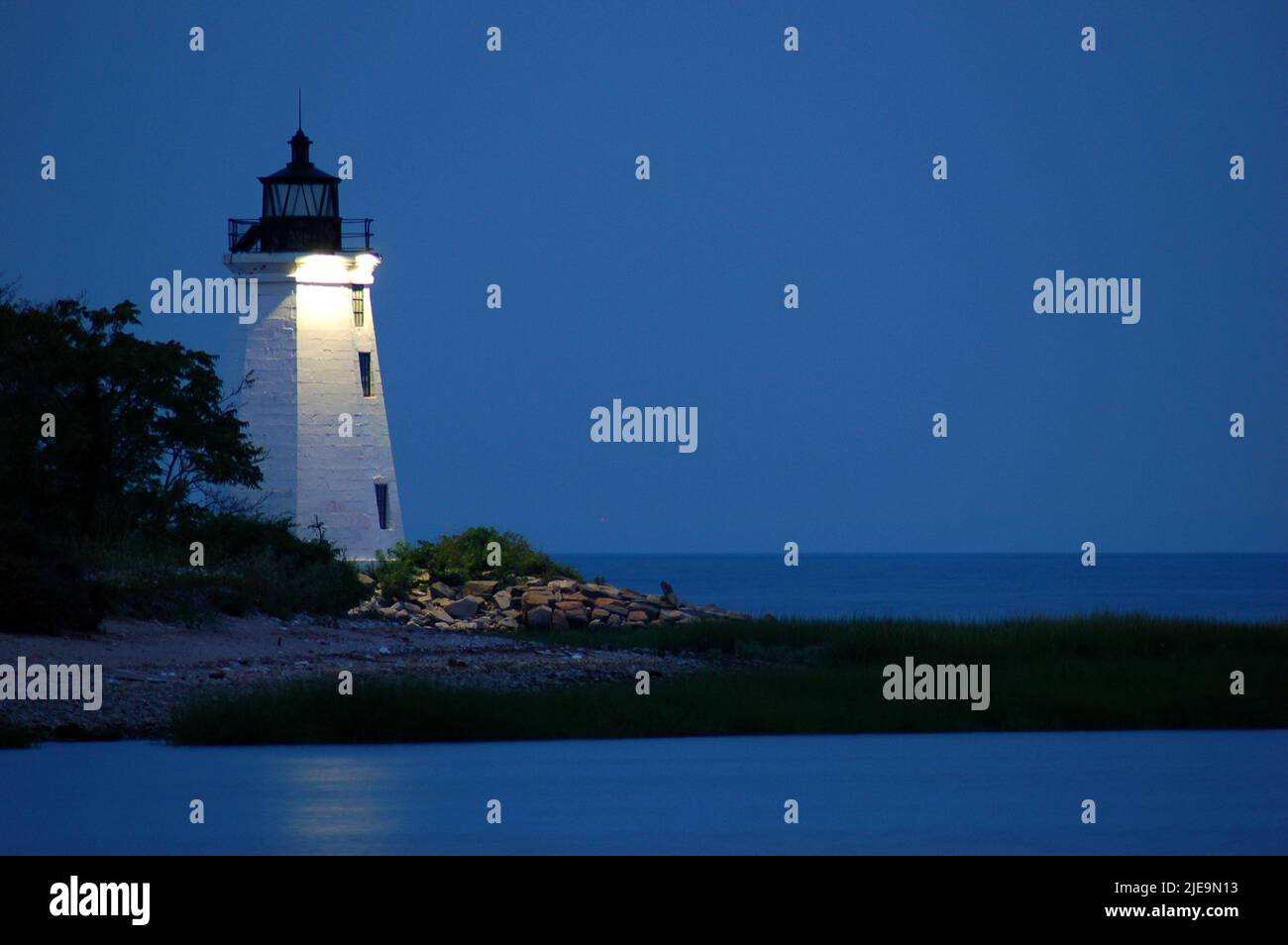 Der Leuchtturm von Bridgeport, auch bekannt als das Black Harbour Light, leuchtet am Strand des Long Island Sound gegen den Abendhimmel Stockfoto