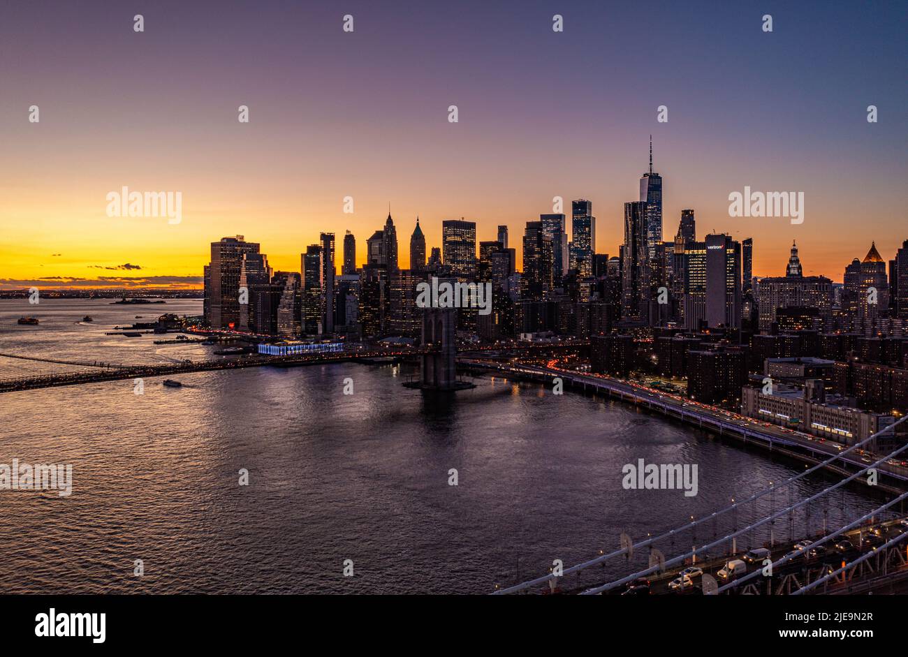 Die Wolkenkratzer in Lower Manhattan sind Silhouetten vor dem farbenfrohen Sonnenuntergang. Starker Verkehr auf Straßen entlang des Wassers. Manhattan, New York City, USA Stockfoto