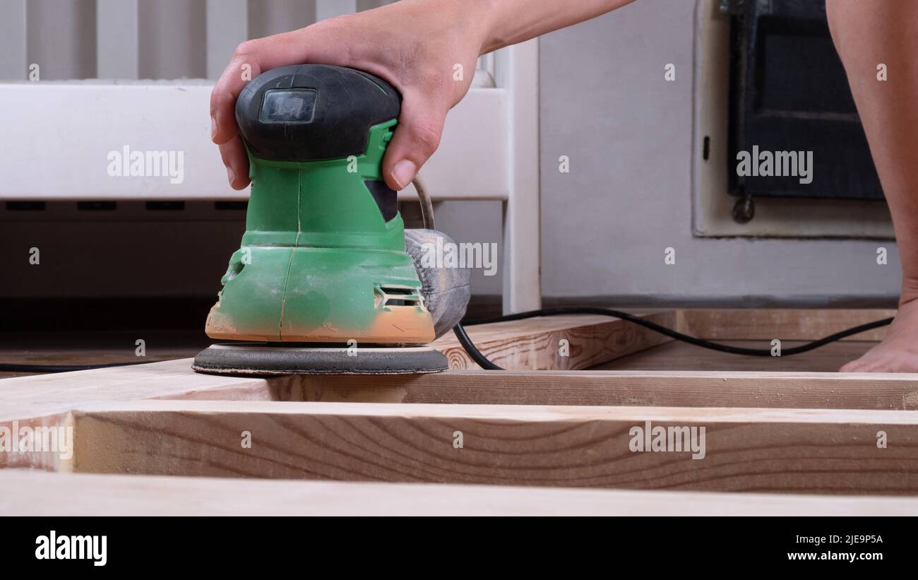 Entfernen des Lackes aus dem Holz, Bearbeiten und Polieren des Holzes mit dem Schleifer. Stockfoto