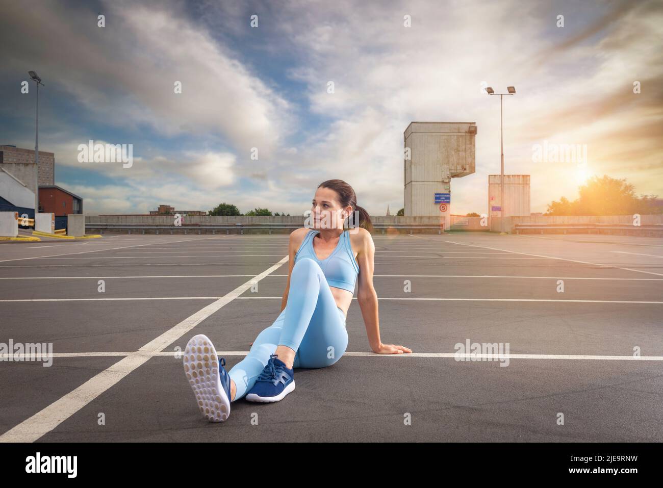 Sportliche Frau sitzt und entspannt nach dem Training, städtischer Hintergrund Stockfoto