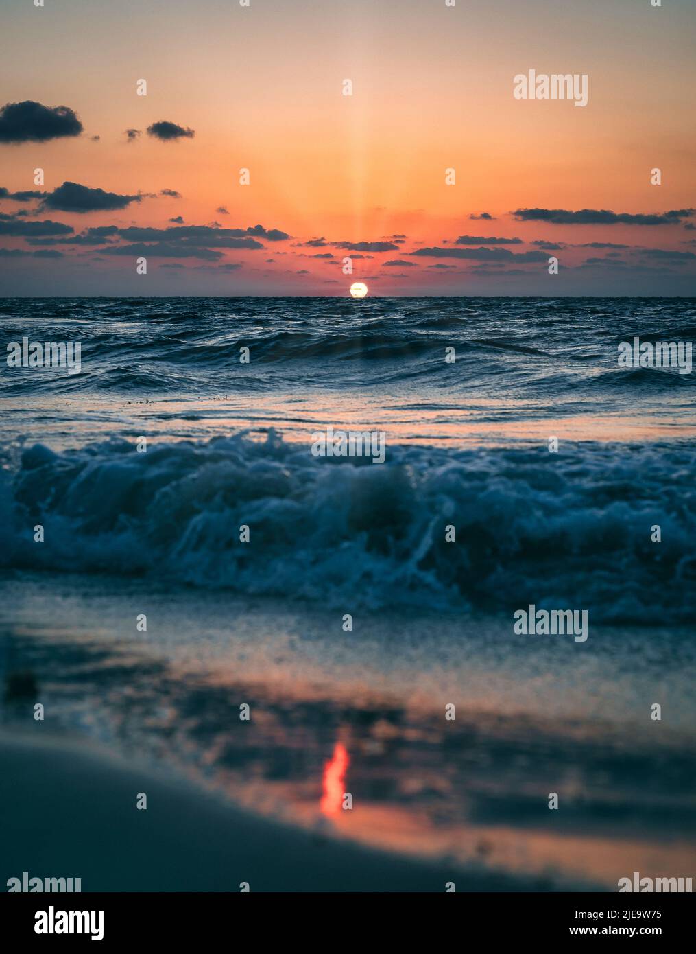 Farbenprächtiger Sonnenaufgang an einem karibischen Strand mit bewölktem Himmel und Sonnenstrahlen mit Lichtreflexion auf dem Sand im Sian Kaan Nationalpark in der Nähe von Tulum Stockfoto