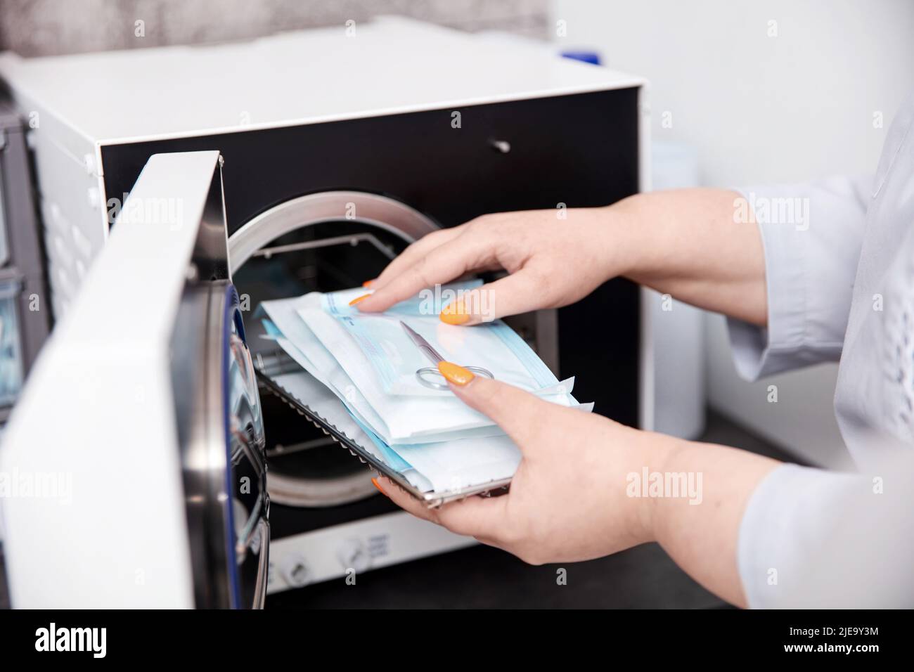 Nach der Sterilisation nehmen die Werkzeuge mit den Händen aus dem Autoklav Stockfoto