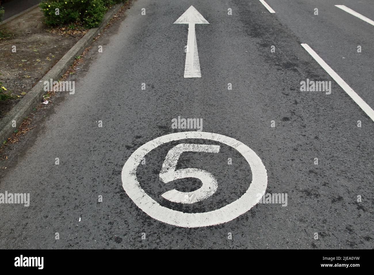 5 Meilen pro Stunde Tempolimit und ein Pfeil mit weißer Straßenfarbe auf dem Tarmac eines Supermarket Car Park in der Nähe von Edinburgh, Schottland Stockfoto