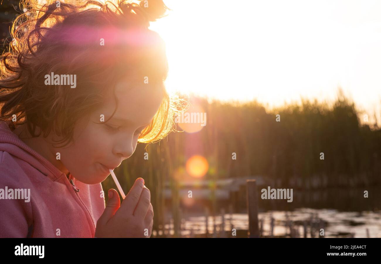 Porträt eines kleinen Mädchens vor dem Hintergrund der Abendsonne, Erholung im Freien am Fluss. Stockfoto