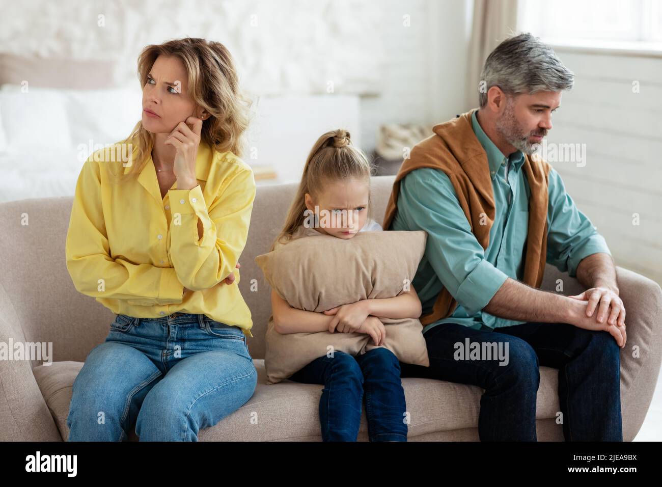 Unglückliche Eltern Mittleren Alters Und Kleine Tochter Sitzen Zu Hause Stockfoto