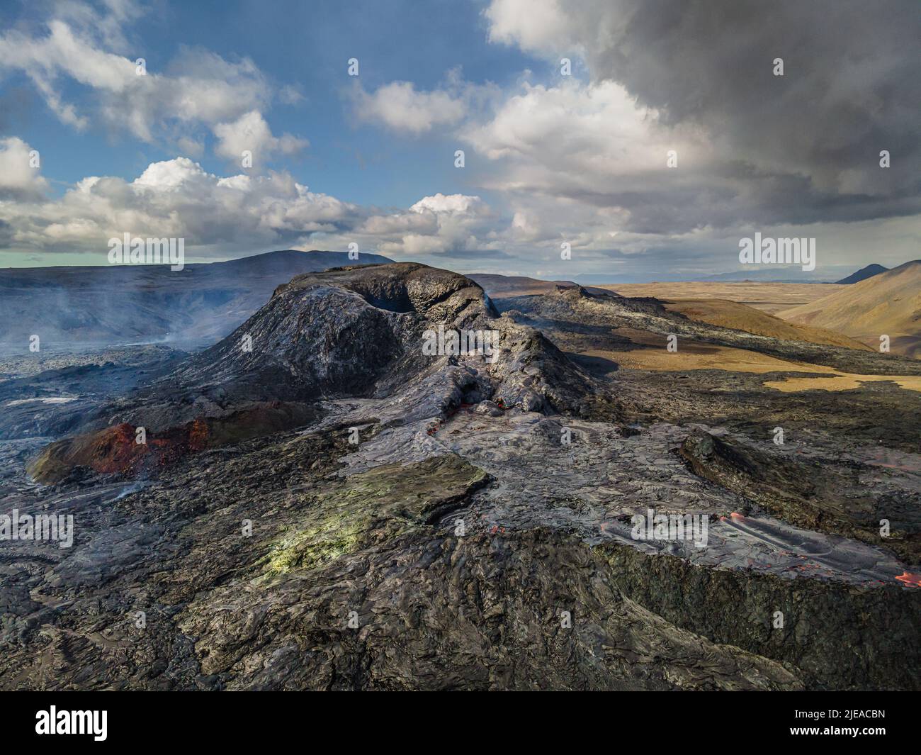 Landschaft mit aktiven Kratern auf der isländischen Halbinsel Reykjanes. Gekühlter Lavastrom um den Krater mit einzelnen Dampfsäulen. Sonnentag mit cl Stockfoto