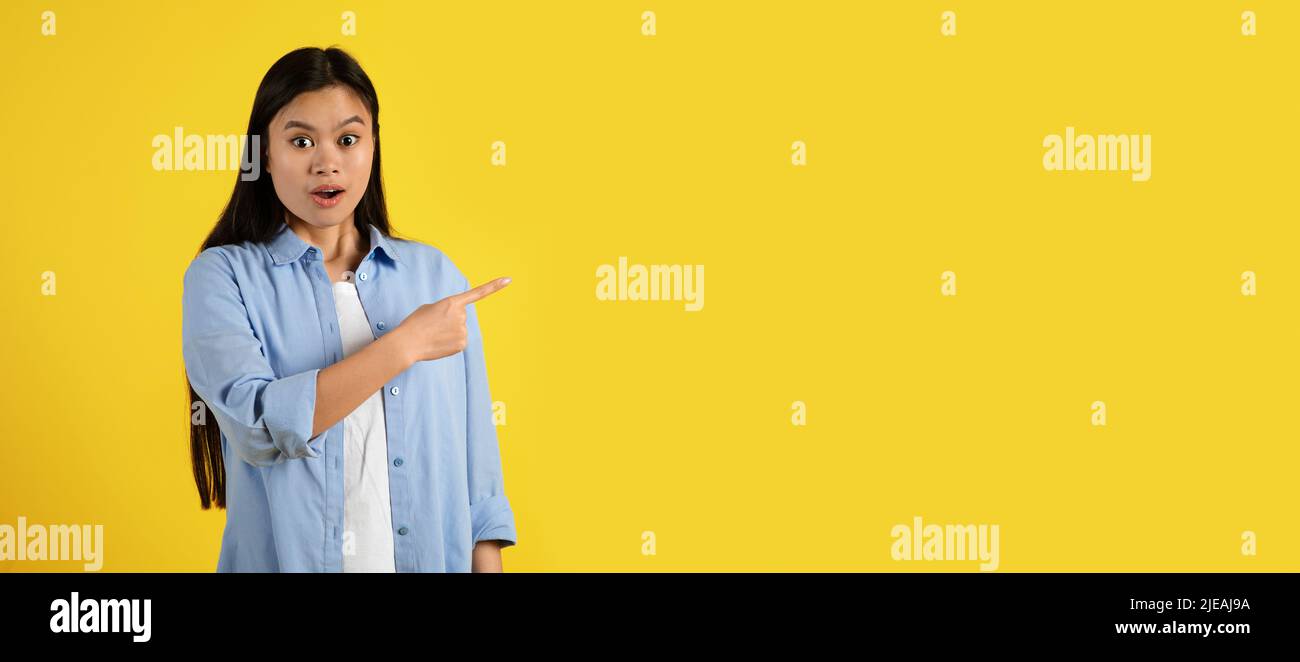 Froh überrascht lustige junge japanische Frau mit offenem Mund, Zeigefinger auf leeren Raum Stockfoto