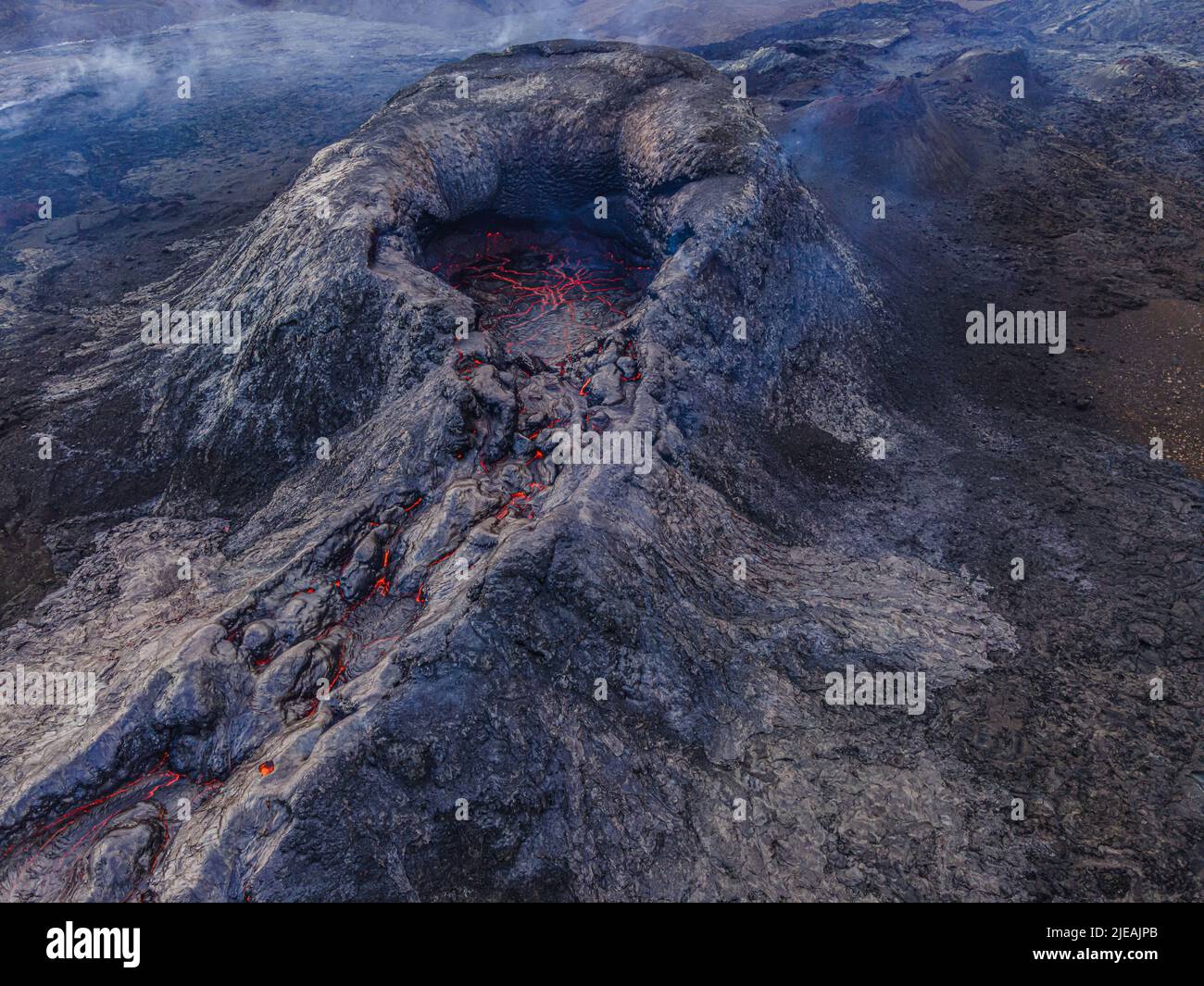 Blick auf den Vulkankrater. Strukturen aus roter Lava in der Krater-Mündung. Vulkan kurz vor Ausbruch. Dunkler, abgekühlter Magmagestein um den Krater. Stockfoto