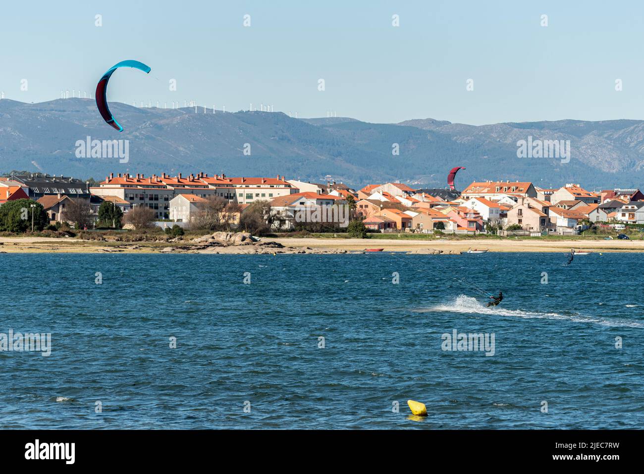 Zwei Leute üben Kitesurfen vor einem Strand in spanien Stockfoto