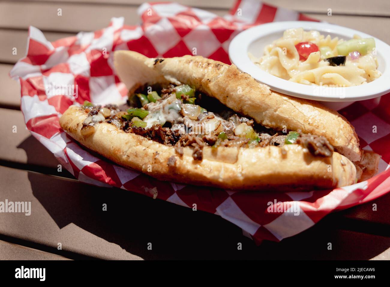 Ein Philly Cheesteak-Sandwich mit einer Beilage Nudelsalat in einem Retro-Korb Stockfoto