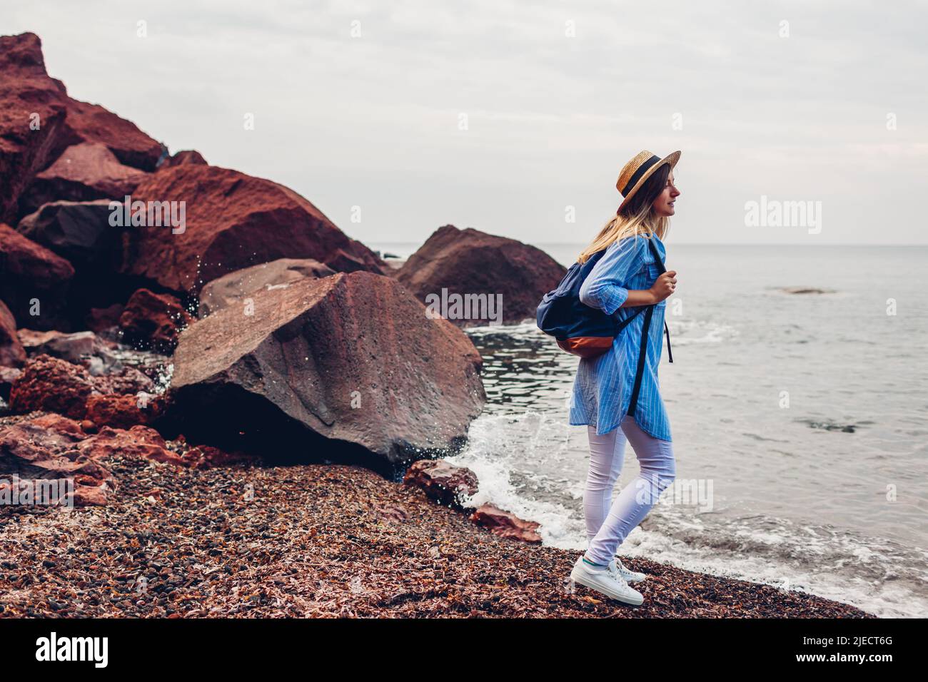 Frau, die auf der Insel Santorini, Griechenland, den Roten Strand und die Meereslandschaft genießt. Tourismus, Sommerreisen Stockfoto