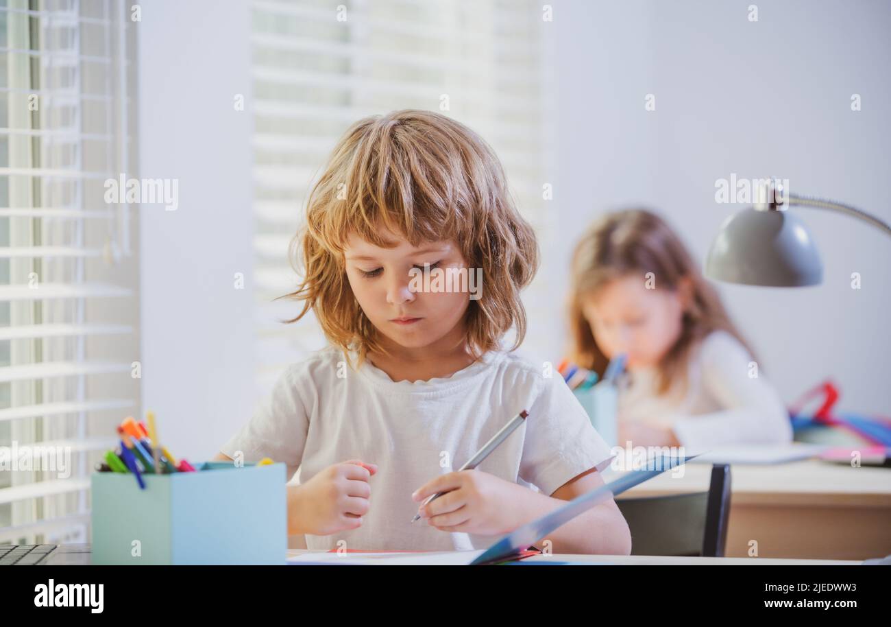 Nette Schüler schreiben am Schreibtisch im Klassenzimmer in der Grundschule. Student Junge macht Test in der Grundschule. Kinder schreiben während des Unterrichts Notizen Stockfoto