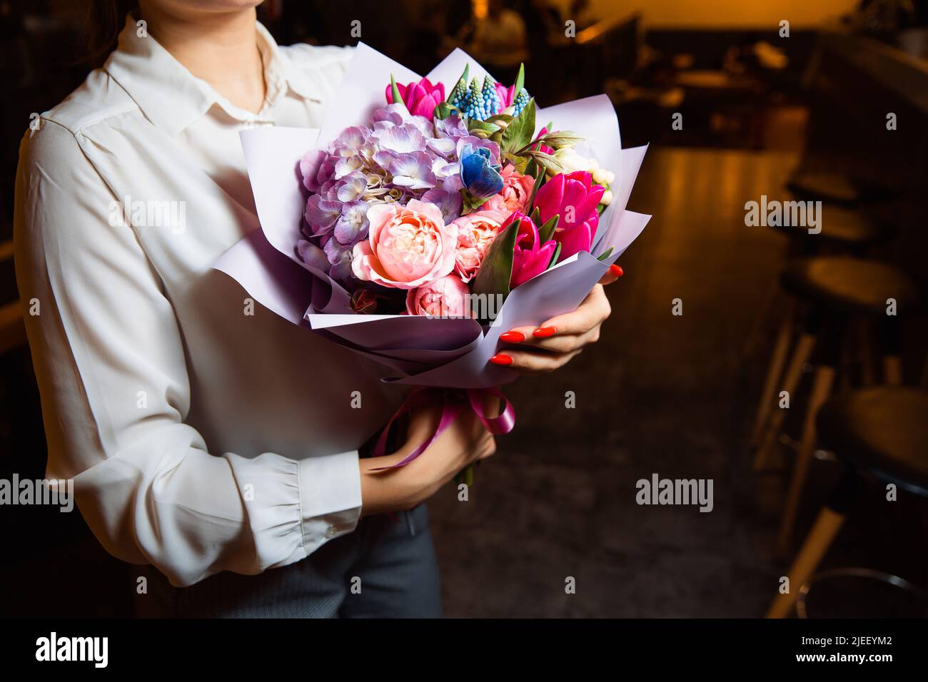 Das Mädchen hält in ihrer Hand einen herrlichen Strauß mit bunten frischen Blumen Stockfoto