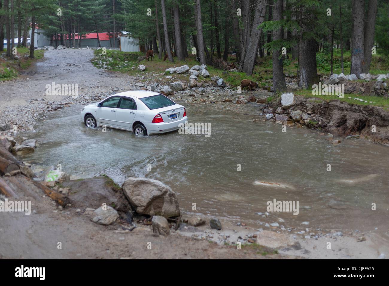 KUMRAT VALLEY, KPK, Pakistan - 11. Juni 2022: Toyota Corolla überquert Wasser im Wald und fährt zum Kumrat Valley in Pakistan Stockfoto