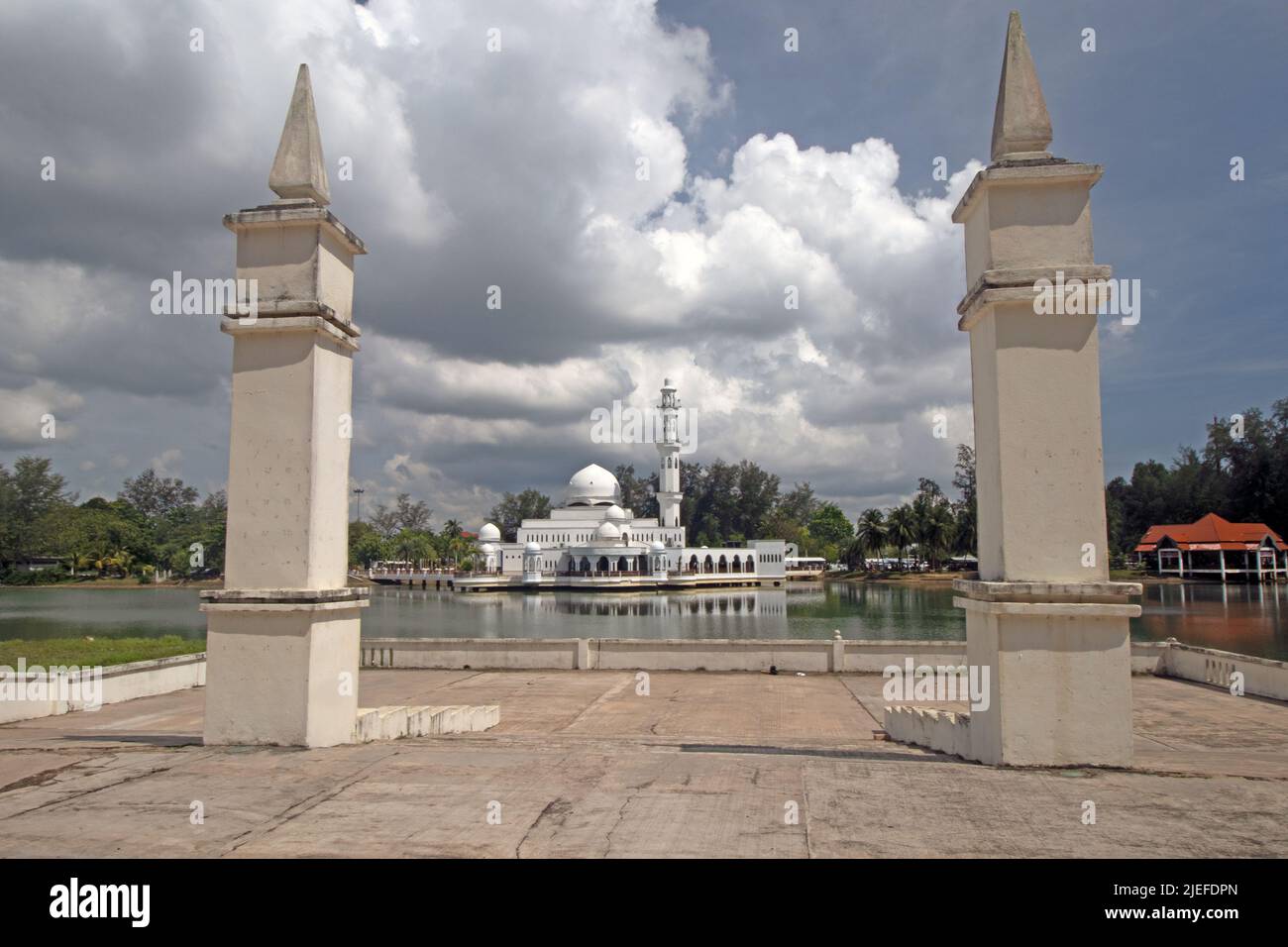 Säulen eines schwimmenden Pavillons mit der Kuala Ibai schwimmende Moschee unter schweren Wolken in Kuala Ibai in Kuala Terengganu, Malaysia. Stockfoto