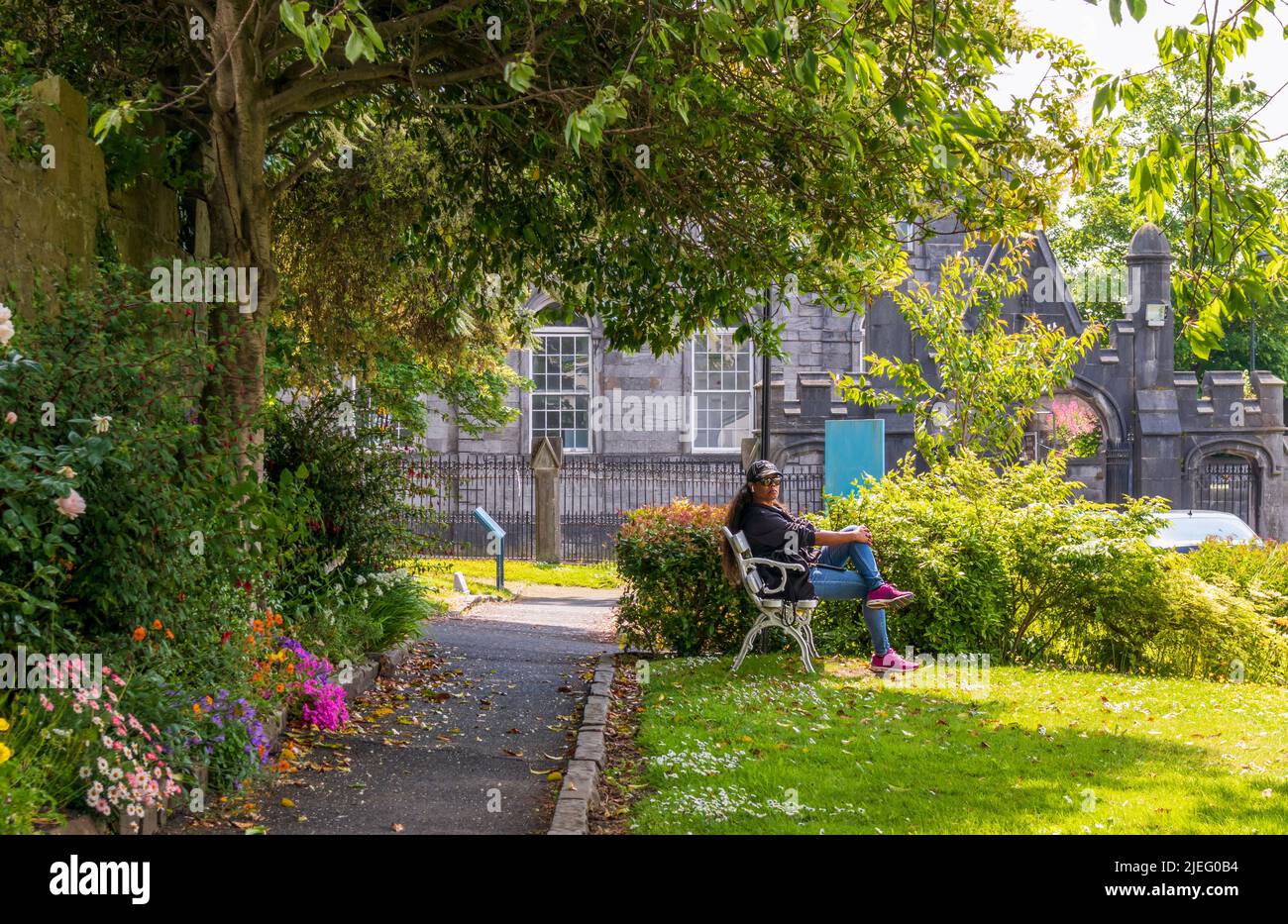 Limerick, Irland - 4. Juni 2022: Eine Frau, die sich im schönen Garten in der Nähe der St. Mary's Cathedral in Limerick, Irland, ausruhte Stockfoto