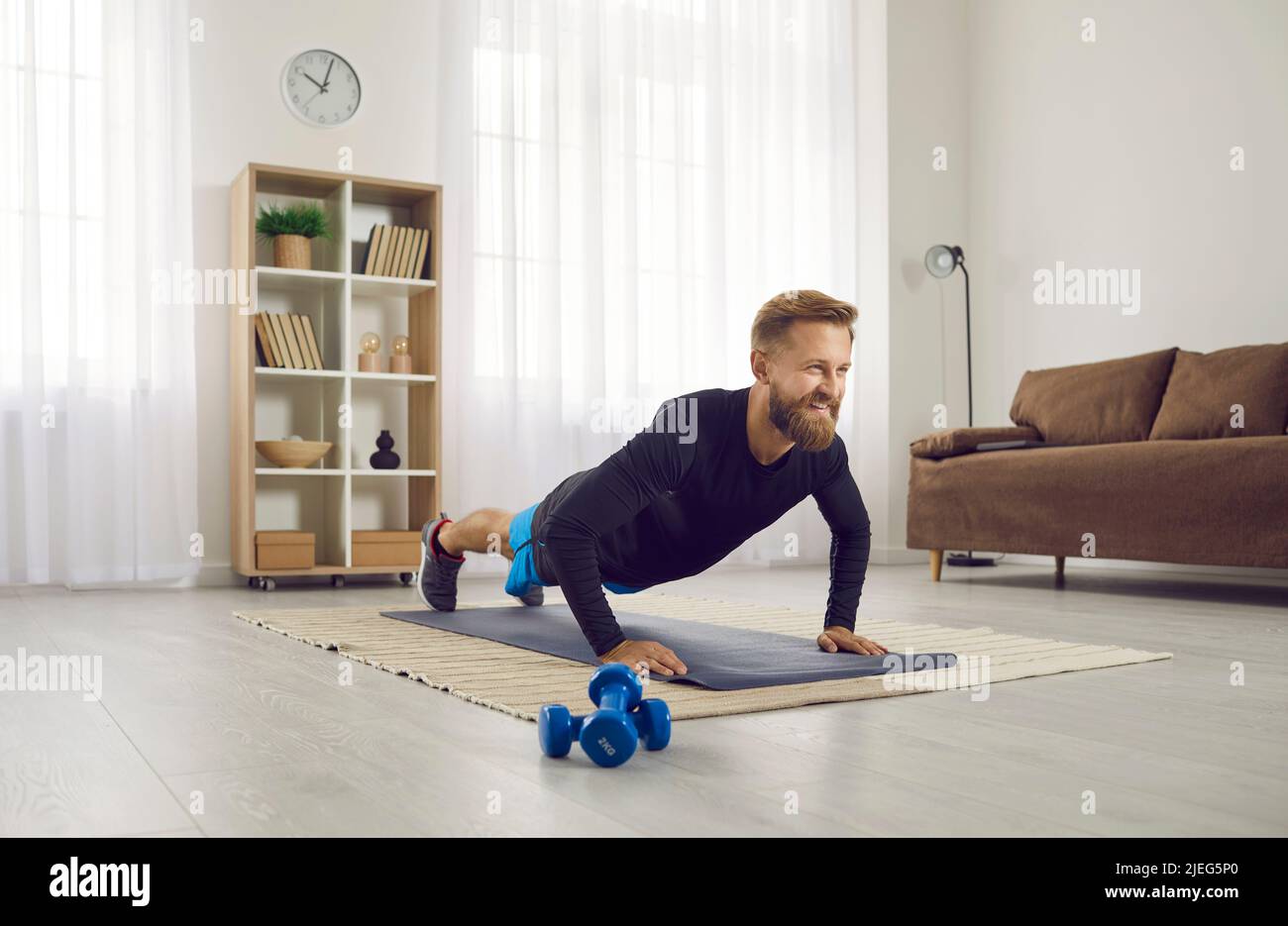 Lächelnder, straffer Mann trainiert zu Hause Sport Stockfoto