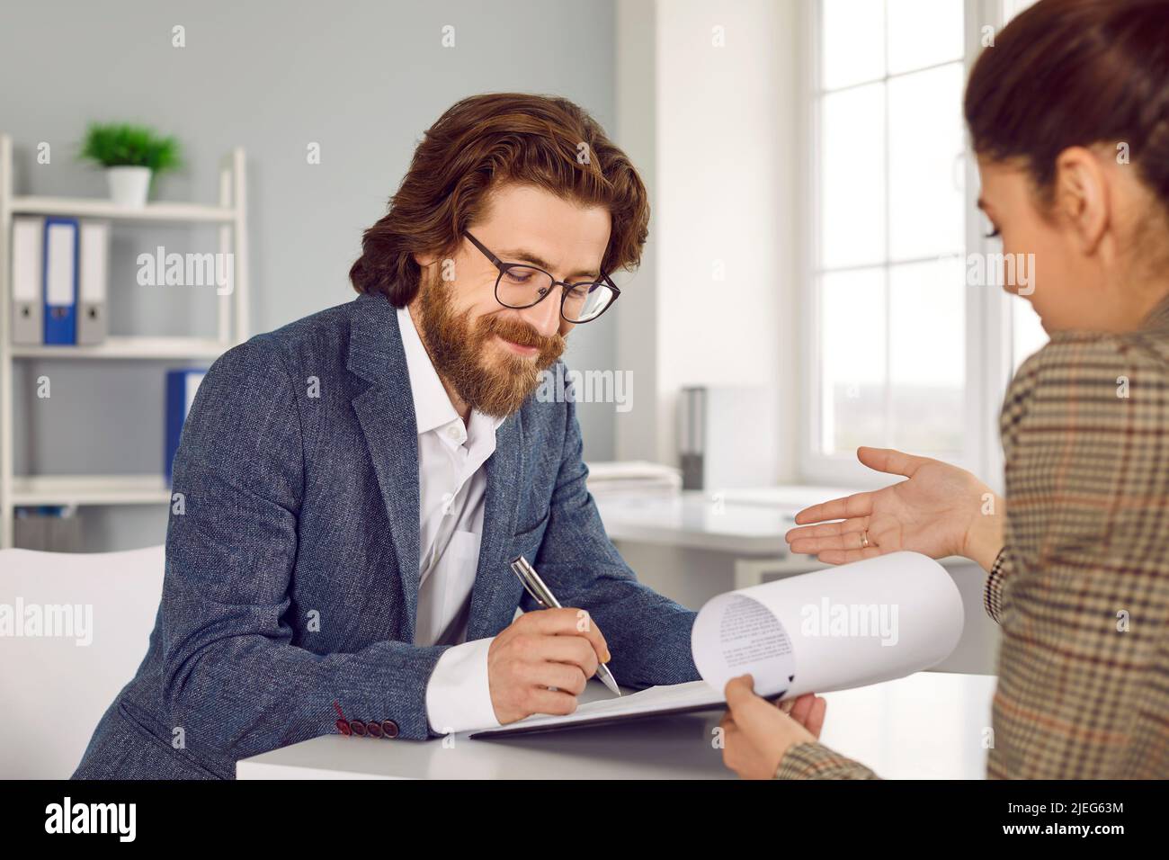 Glücklicher Geschäftsmann unterzeichnet Vertragsvereinbarung bei Kreditmakler oder Versicherungsmakler Büro Stockfoto